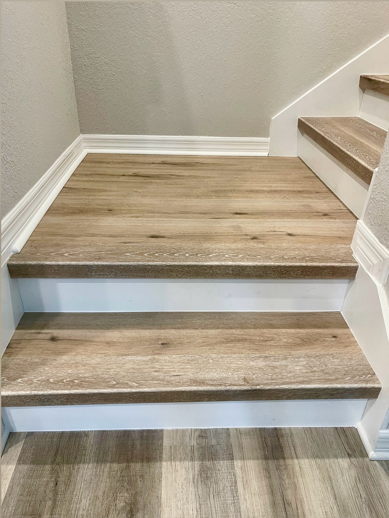 Wood-look stair treads and white risers installed by Vial Construction